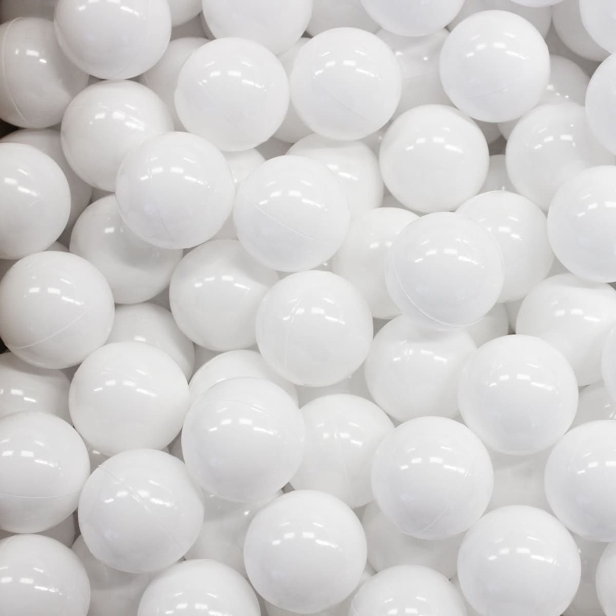 Close-up of numerous shiny white plastic ball pit balls. Spheres fill the frame, reflecting light on their surfaces
