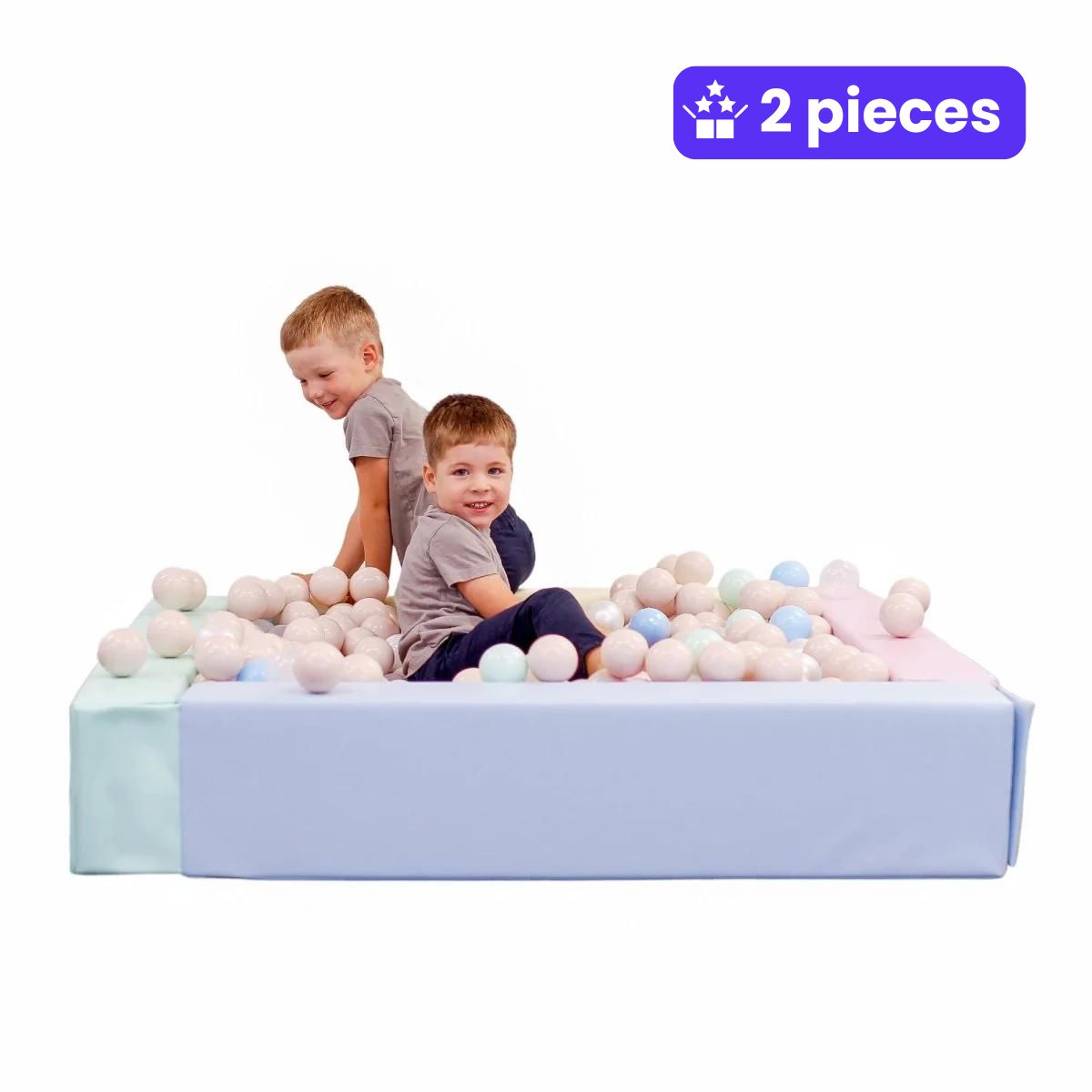 Two smiling boys in gray shirts play in a pastel, square, soft play ball pit. Foam blocks in mint and lavender colors