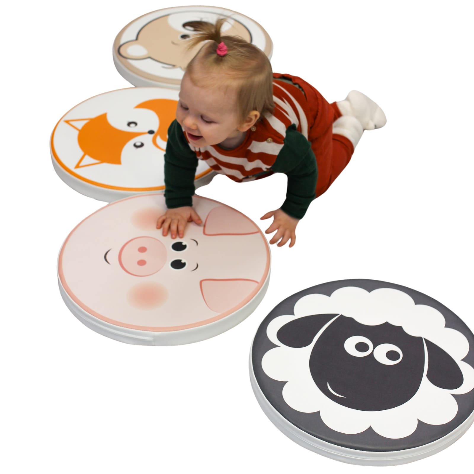 A joyful toddler crawling on soft play cushions. Each cushion has a printed animal face including fox, sheep, bear and a pig