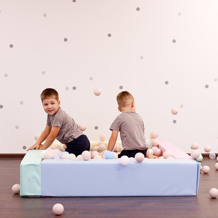 Twin boys playing in pastel color IGLU ball pit