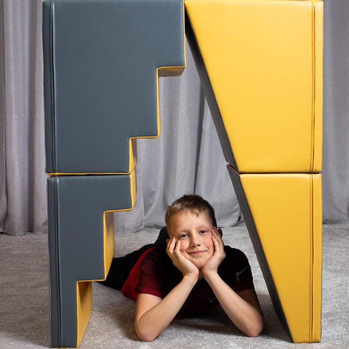 A boy is engaging in imaginative play under the IGLU Soft Play 4 Piece Soft Play Step and Slide Set - Transformer.