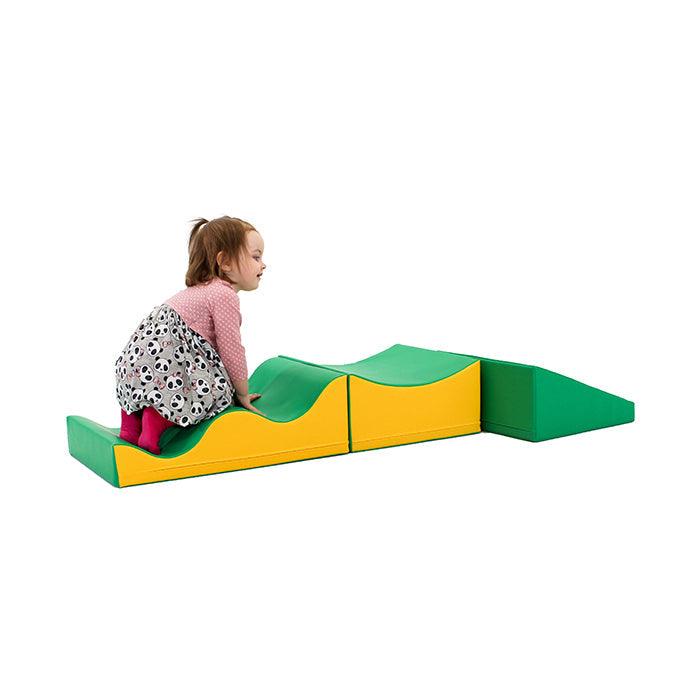 A little girl is playing on the IGLU Soft Play - Wave Venture slide.