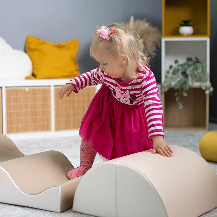 A little girl is playing with a IGLU Soft Play soft play shapes toy in a room.