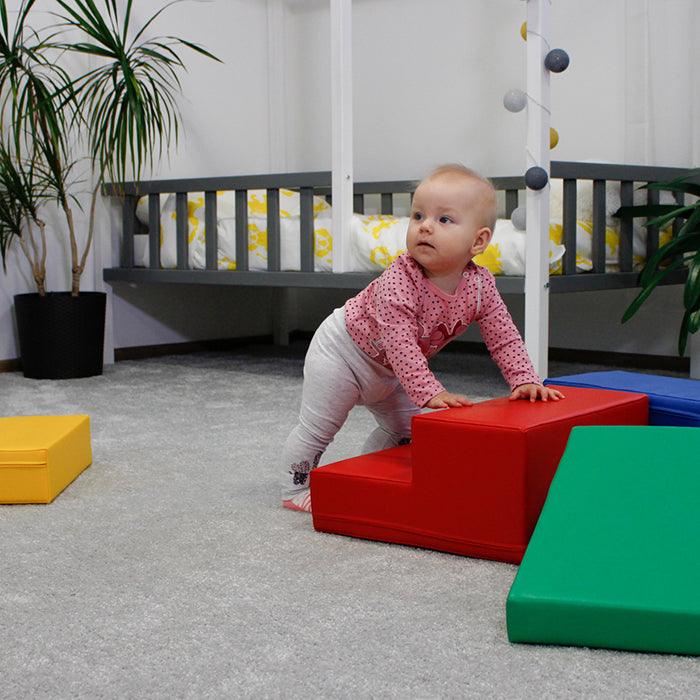 A baby is developing gross motor skills by playing with the IGLU Soft Play Soft Play Foam Block Set - Corner Climber in a room.