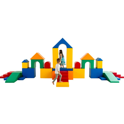 Children play on a large, colorful soft play castle made of yellow, blue, green, and red blocks with arches, ramps, and steps