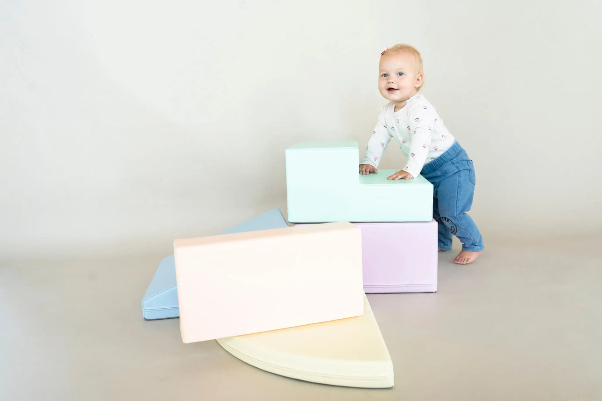 Mamma sēž uz grīdas blakus mazulim un Soft Play komplektam