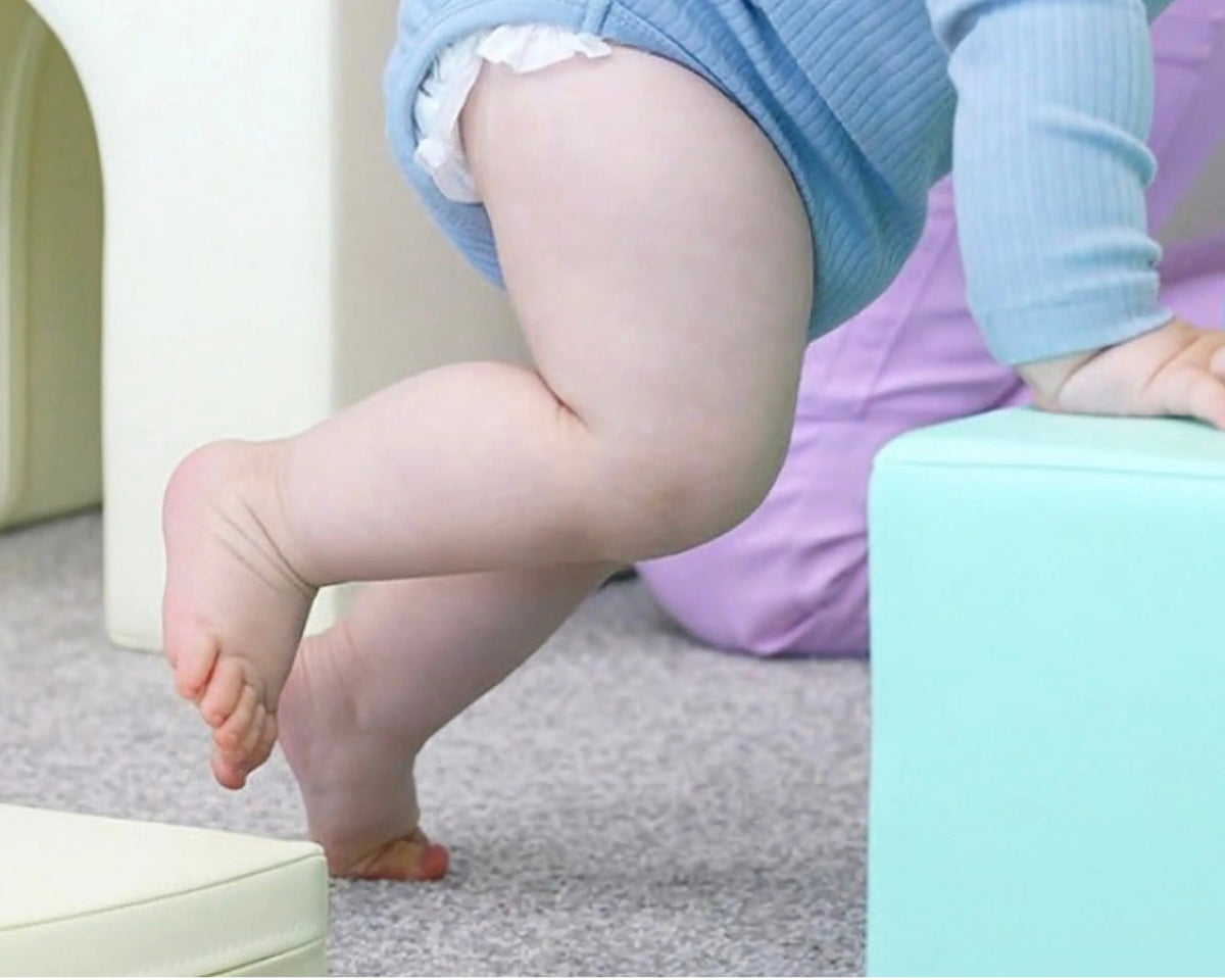 Barefoot toddler standing on a soft play surface