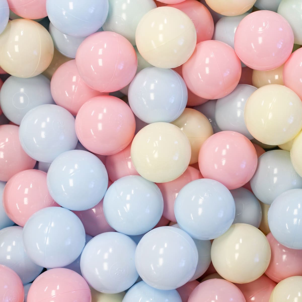 Close-up of numerous shiny pastel-colored plastic ball pit balls. Spheres fill the frame, reflecting light on their surfaces