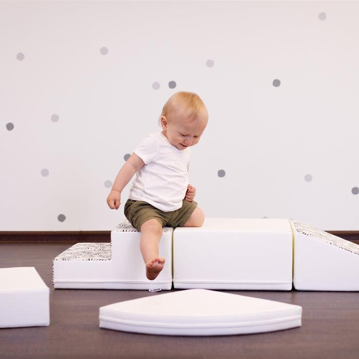 A baby boy playing on a white IGLU set