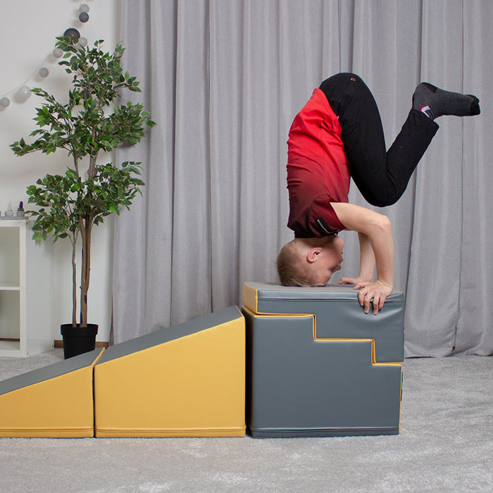 A boy engaging in imaginative play while performing a challenging handstand on the IGLU Soft Play 4 Piece Soft Play Step and Slide Set - Transformer.