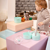 Ein junges Mädchen, das beim Spielen mit einem IGLU Soft Play Soft Play Foam Block Set - Corner Climber Spielzeug auf einem Kistenstapel seine Koordination und Grobmotorik entwickelt.