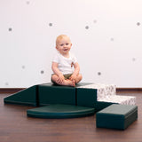 Ein Baby, das mit einem dunkelgrünen IGLU Set spielt